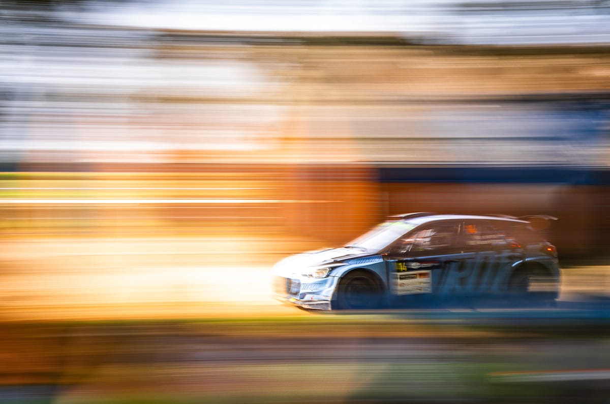 Rallyauto scherp vastgelegd met panningtechniek tegen een uitgevloeide achtergrond