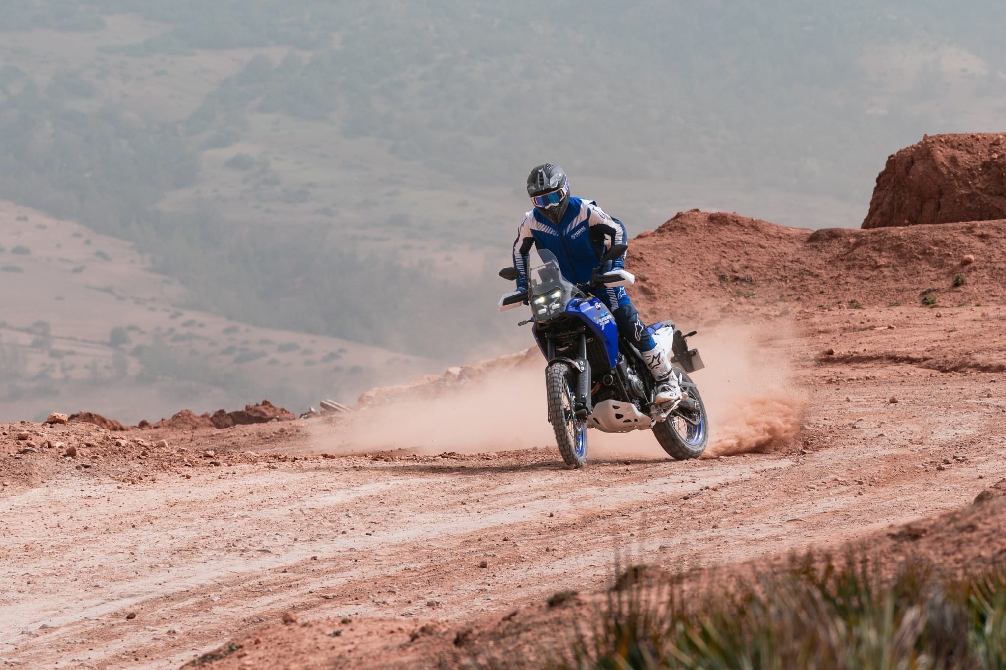 Yamaha Ténéré 700 in een stofwolk op een rode gravelweg in Marokko